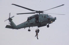 Search-and-rescue swimmers from Atsugi-based HS-14 are hoisted into their helicopter during annual SAR jump training outside Yokosuka Naval Base.