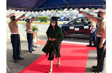 Kubasaki High School senior Tina Davis is saluted with a Marine sabre arch while accepting her diploma during a drive-thru ceremony at Camp Foster, Okinawa, Saturday, June 6, 2020.