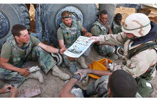 In a 2003 photo, Command Sgt. Maj. John Sparks delivers copies of Stars and Stripes to U.S. Marines from Weapons Platoon, 3-2 India Company.