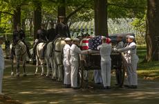 Navy honor guard members stand around a caisson carrying a casket containing the remains of four Vietnam War veterans whose missing remains were accounted for after extensive search and identification efforts that spanned several decades.