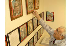 At Kadena Air Base, educator Greg Apkarian reaches for a picture frame that has a personalized autograph of architect Buckminster Fuller, featured on a 1964 Time magazine front cover.