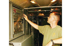Sgt. James Buchanan flips on the power inside a 20-foot long by 7-foot wide tactical air operations module used in Afghanistan to monitor air traffic and aid command and control.