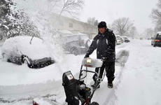 Air Force Master Sgt. Greg Pocaigue uses a snowblower to dig out his car.