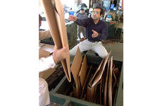 Customer Shinobu Sashida helps load a compactor that scrunches cardboard boxes into 1,100-pound recyclable bales.