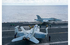 An EA-18G Growler launches while sailors taxi another Growler to an adjacent catapult on the USS John C. Stennis flight deck on June 5, 2016, in the South China Sea.