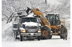 Workers move thousands of pounds of snow into one of a line of dumptrucks in the parking lot of the Army and Air Force Exchange store at Misawa Wednesday morning.