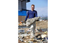 Civilian volunteer Alex Chamberlain, a member of the Misawa Air Base community, lugs a big chunk of concrete while helping clean the tsunami-ravaged Noda Village during a base-sponsored trip on Friday.