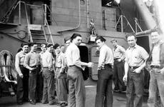 Crewmen of the USS Concord stand on the main deck below a statue of a minuteman mounted on the bulkhead, in this photo taken during the last 15 months of World War II.