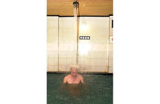 A man relaxes under a jet of water spraying from the ceiling into a pool at the Seolbong Onchon Tourist Hotel.