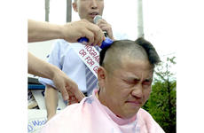 Lim Jong-han, a property owner, winces as other demonstrators protesting a new Army housing program shave his head Tuesday outside the gates of Yongsan Garrison.