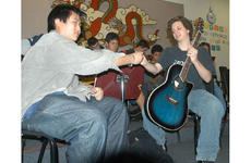 Kang Han-sul, left, a student at the German foreign school in Seoul, hands L.J. Christie a guitar in teacher Lisa Riehle's guitar class.