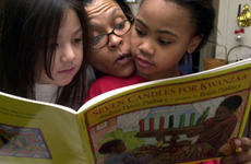 Juana Cephus (center) reads a book about Kwanzaa on Friday with her 8-year-old daughter, Raquel, right, and Raquel's friend, Azlyn Heidt, also 8, at Cephus; home in the Sagamihara Housing Area near Camp Zama, Japan.