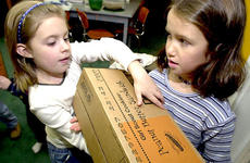 Allison Couch, left, and Melissa Patten lug boxes of Girl Scout cookies into the group's building at Atsugi Naval Air Facility, Japan, on Tuesday.