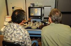Pedro Loureiro, Ph.D. (left), Archivist at the Defense Imagery Management Operations Center (DIMOC) and Jeff Sotzing, Chief Executive Officer at Carson Entertainment Group, review a 1963 film of The Tonight Show Starring Johnny Carson that was once thought lost, but was found earlier this year. DIMOC turned over the film to Sotzing to be added to the Carson archives.