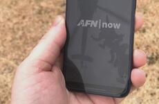 A hand holds a cellphone with the AFN app on it.