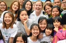 A Navy public affairs officer poses for a photo with children at the Dorothea's Project Legacies Charity Center, Danang, Vietnam, during the USS Theodore Roosevelt's port call March 6, 2020.