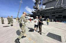 Sailors pose with the USS Theodore Roosevelt after the San Diego-based aircraft carrier arrived at Naval Base Guam, Tuesday, Feb. 6, 2024. 