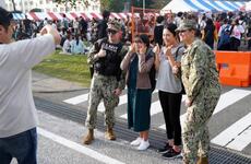 Visitors pose with Navy security during the 44th Friendship Day celebration at Yokosuka Naval Base, Japan, Sunday, Oct. 16, 2022. 