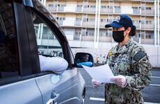 A sailor practices screening drivers for coronavirus symptoms at Yokosuka Naval Base, Japan, March 18, 2020.