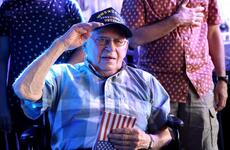 World War II veteran Arthur Grabiner salutes while holding an American flag.