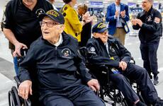Two military veterans in wheelchairs are greeted at the airport.