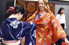 A Japanese service member helps Maj. Michelle Binder wear a yukata during a cultural exchange at the USO on Yokota Air Base, Japan, July 22, 2023. 