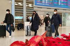 Airplane passengers exit an arrival gate wearing masks at Incheon International Airport, South Korea, Monday, Feb. 3, 2020.