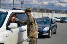 A 2nd Infantry Division soldier checks for a temperature as dozens of vehicles line up to enter the Dongchang-ri gate at Camp Humphreys, South Korea, Wednesday, Feb. 26, 2020.