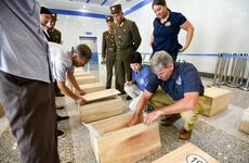 Forensic anthropologists with the Defense POW/MIA Accounting Agency review the contents of cases containing the possible remains of service members lost in the Korean War during a unilateral transfer in Wonsan, North Korea, in July 2018.