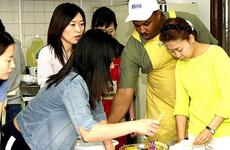 Marvin Sanders, center, walks a group of new brides through the cooking portion of the USO's Cross-Cultural School at Camp Kim, South Korea.