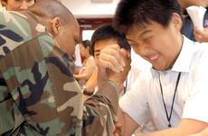 Sgt. Robert E. Owens Jr., with the U.N. Command, Military Armistice Commission at Camp Bonifas, arm-wrestles a South Korean high school student Wednesday in Seoul during the USO Good Neighbor Program.