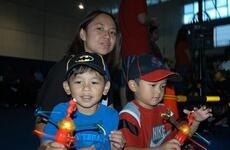 Jermaine Aterrado, 4, (left), and his brother Cedrick, 3, are lost in their glow toys before the  Sesame Street/USO Experience for Military Families show Oct. 6, 2011, at Sasebo Naval Base, Japan. Their mother, Jinky Aterrado, looks on.