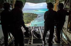 Loadmasters with the 36th Airlift Squadron out of Yokota Air Base, Japan, watch bundles parachute down to Nomwin, Federated States of Micronesia, Dec. 13, 2019, during the annual Operation Christmas Drop.