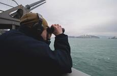 A U.S. sailor stands lookout aboard an aircraft carrier.