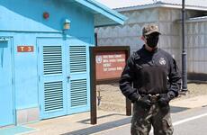 A South Korean soldier stands guard in front of a blue building at the DMZ.