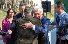 A man with gray hair hugs a general in an Army uniform.