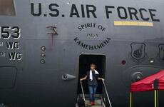 A young man steps out of a C-17 Globemaster II onto stairs. Above the doorway, lettering reads “U.S. Air Force” and “Spirit of Kamehameha.”