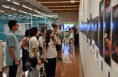 Students and visitors look at photographs on display.
