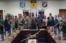 A group of U.S. military members and Guam government officials pose for a photo holding dogs.