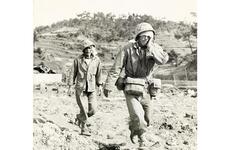 Two injured military members walk to medical treatment.
