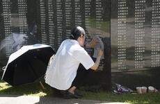 A visitor makes a rubbing of a name on the Cornerstone of Peace monument.