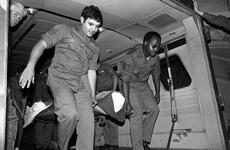 In this black and white photo, men carry a burn victim out of an ambulance.