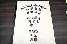 A large booklet that says “Armistice Agreement Maps Volume II” on the cover in black lettering and translated into Chinese and Korean.