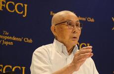 An older man gestures with one hand as he speaks.