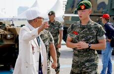 A U.S. Marine veteran shakes hands with a South Korean marine veteran at a ceremony.