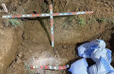 An unexploded bomb is seen being uncovered in the dirt.