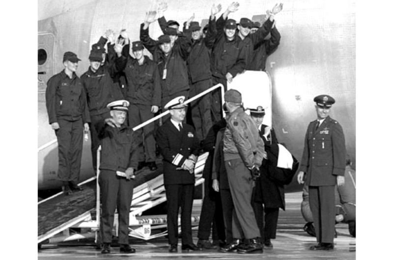 Cmdr. Lloyd Bucher, front left, and USS Pueblo crew members wave to the crowd as they prepare to leave Kimpo Air Base.