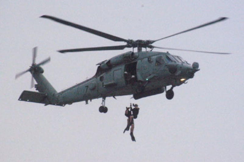 Search-and-rescue swimmers from Atsugi-based HS-14 are hoisted into their helicopter during annual SAR jump training outside Yokosuka Naval Base.