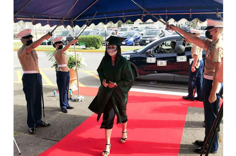 Kubasaki High School senior Tina Davis is saluted with a Marine sabre arch while accepting her diploma during a drive-thru ceremony at Camp Foster, Okinawa, Saturday, June 6, 2020.