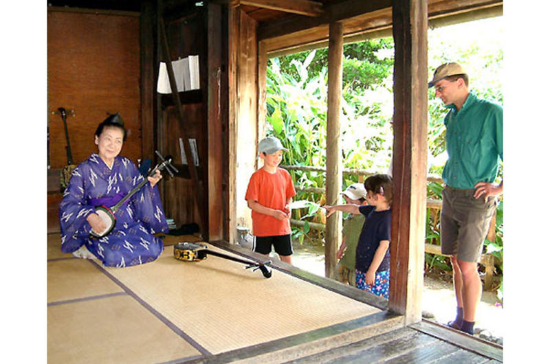 Tomiko Shimabukuro plays the sanshin for a family from Tokyo visiting Ryukyu Mura, a folk village sometimes referred to as Okinawa’s Williamsburg.